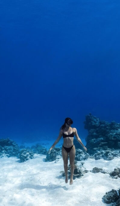 female diver swimming up through the ocean from the sea bed